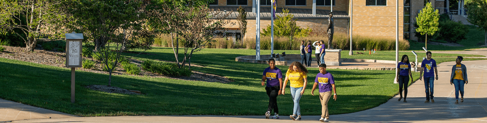 Students with purple and gold WIU t-shirts walking.