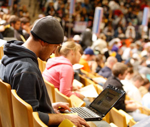 Student in bleachers with laptop at mock election