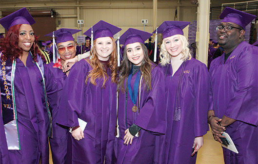 Group photo of students with cap and gowns on at graduation