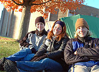 Three students sitting outside residence hall.