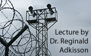 Image of prison fence and tower with the text Lecture by Dr. Reginald Adkisson