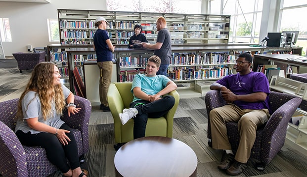 a group of students sitting in comfortable chairs in a library