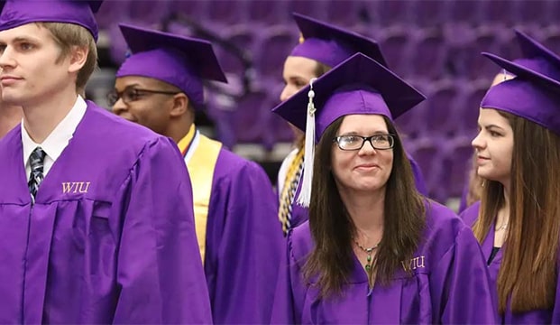 a group of students going through commencement ceremony in purple caps and gowns