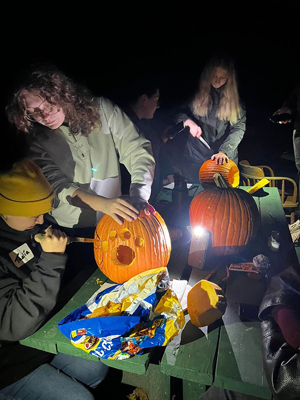students carving pumpkins in the dark at the 2022 Fall Fling event