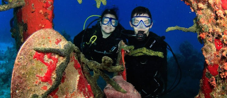 two students SCUBA diving around coral reef