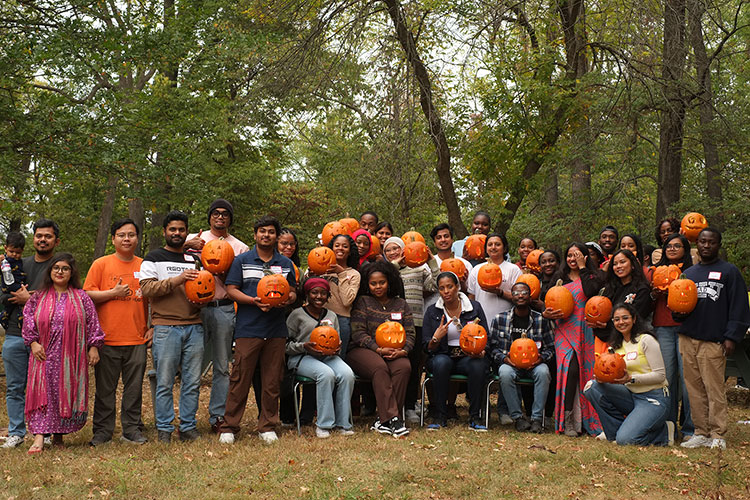 a large group of international students holding carved pumpkins