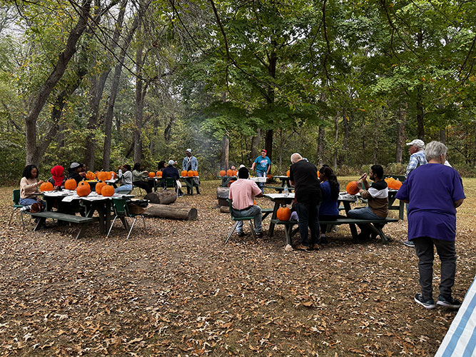 international students carving pumpkins at outdoor picnic tables