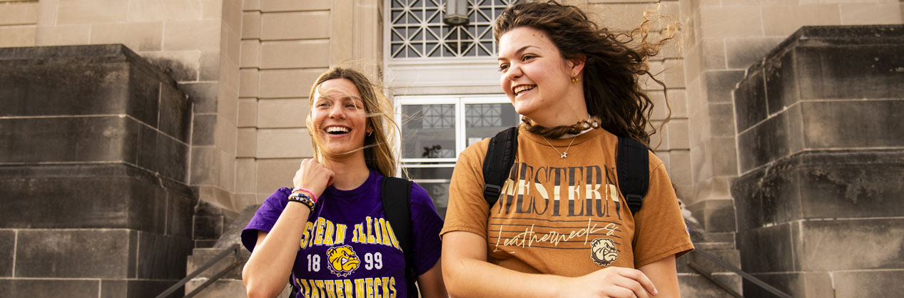 students wearning Western Illinois University shirts standing in front of Garwood Hall