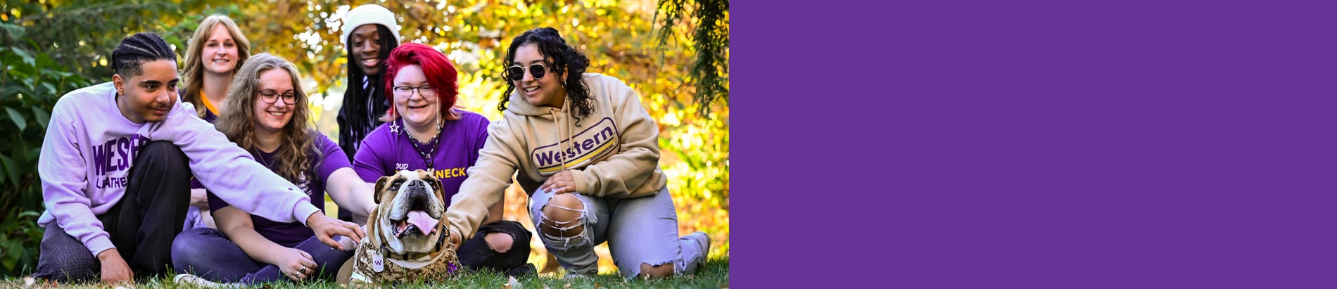 group of student sitting in the grass with WIU's mascot bulldog Col. Rock IV