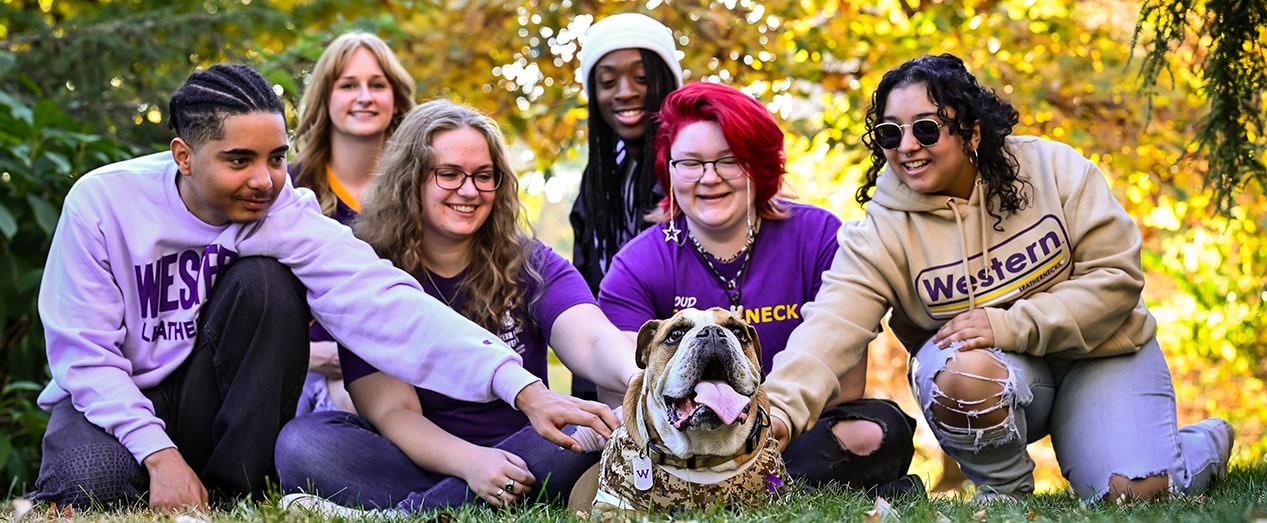 group of student sitting in the grass with WIU's mascot bulldog Col. Rock IV