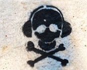 Skull and cross bones wearing headphones graffiti on a wall.