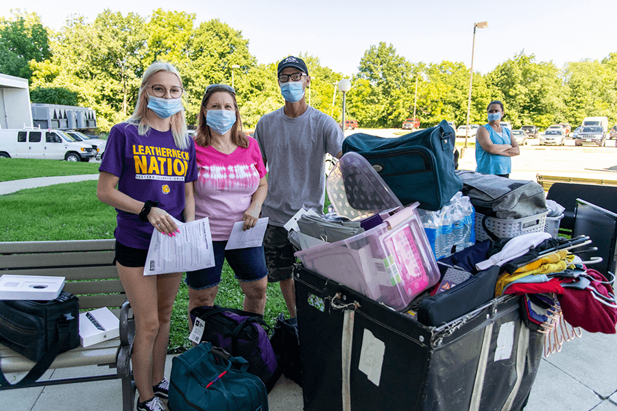 Photo of family with full cart and bags during move in