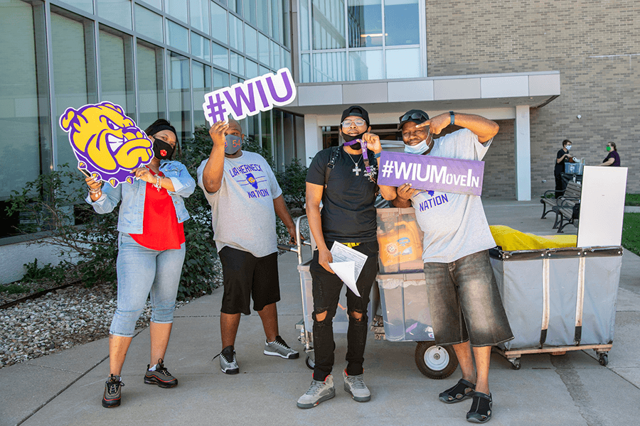 Photo of family moving their kid into their new dorm holding signs with #WIUMoveIn