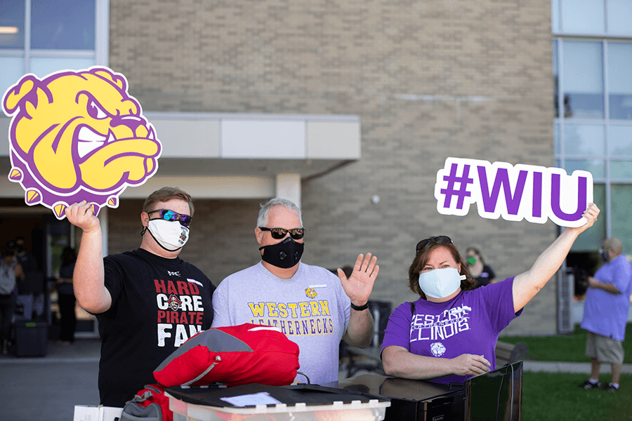 Photo of family with full cart and holding signs of a Rocky head and #WIU