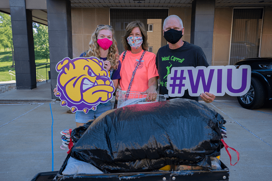 Photo of family with full cart and holding signs of a Rocky head and #WIU