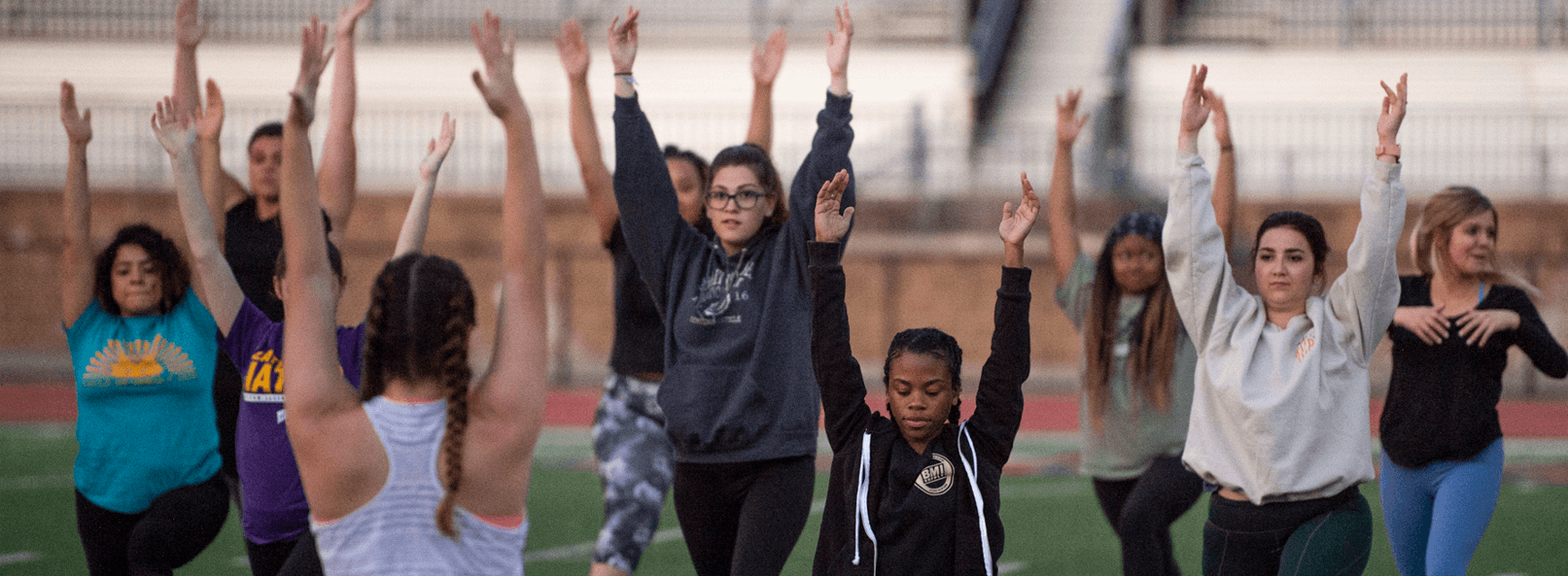 A group of students doing yoga on the football field.