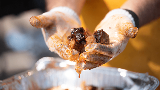 hands holding out bbq burnt ends