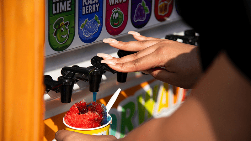 person pouring syrup on a snow cone
