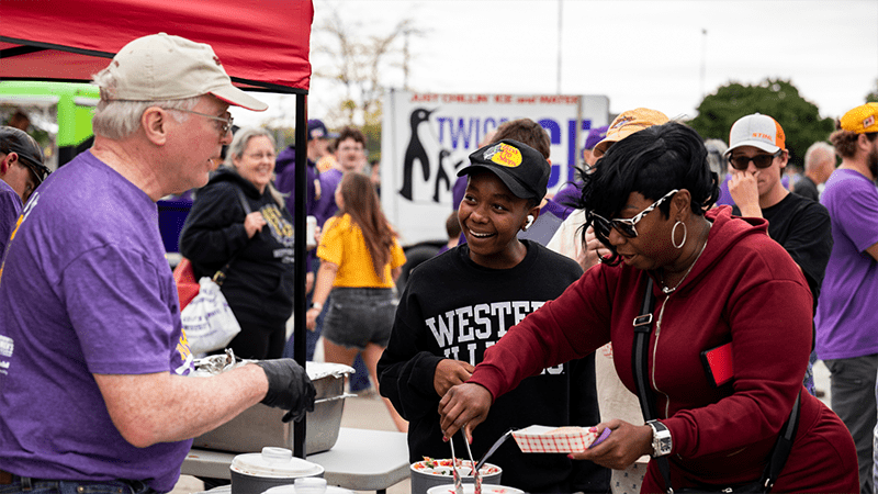 WIU dining cook serving bbq to two people)