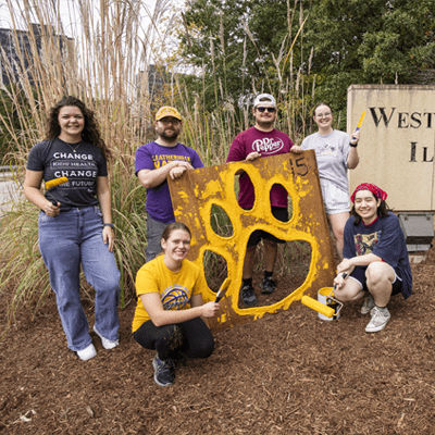 Students painting yellow paws on the road