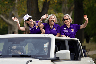 Three women waving from an open top SUV