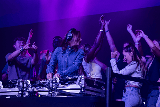 DJ Sophie Gray performing at WestFest 2025 with students dancing around her